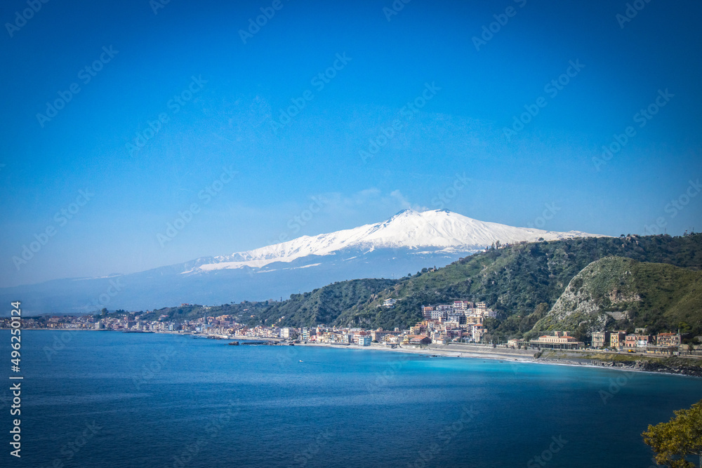 view of mount etna with coastline in foreground, volcano, snow capped, snow, taormina, sicily, italy, europe 