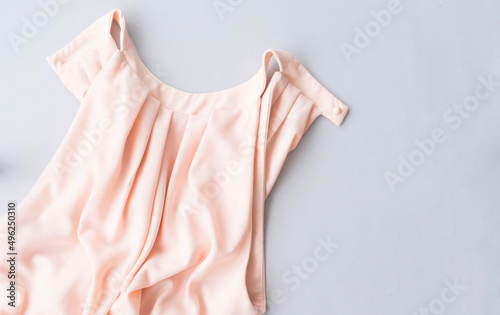 Beautiful female pink blouse or dress lies on a gray background