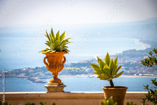 two flowerpots with coastline in background, taormina, sicily, italy, europe 