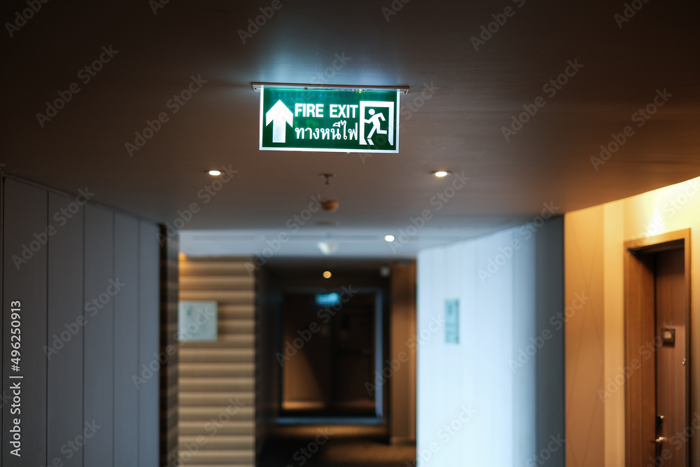 Emergency exit sign at the corridor in building. Green fire exit sign