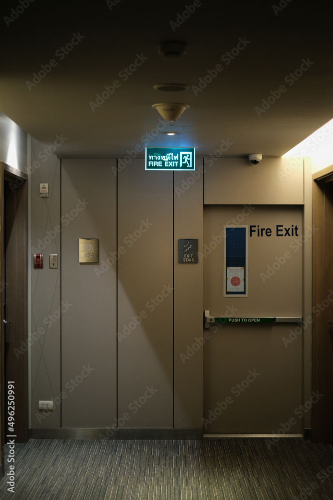 Emergency exit sign at the corridor in building. Green fire exit sign