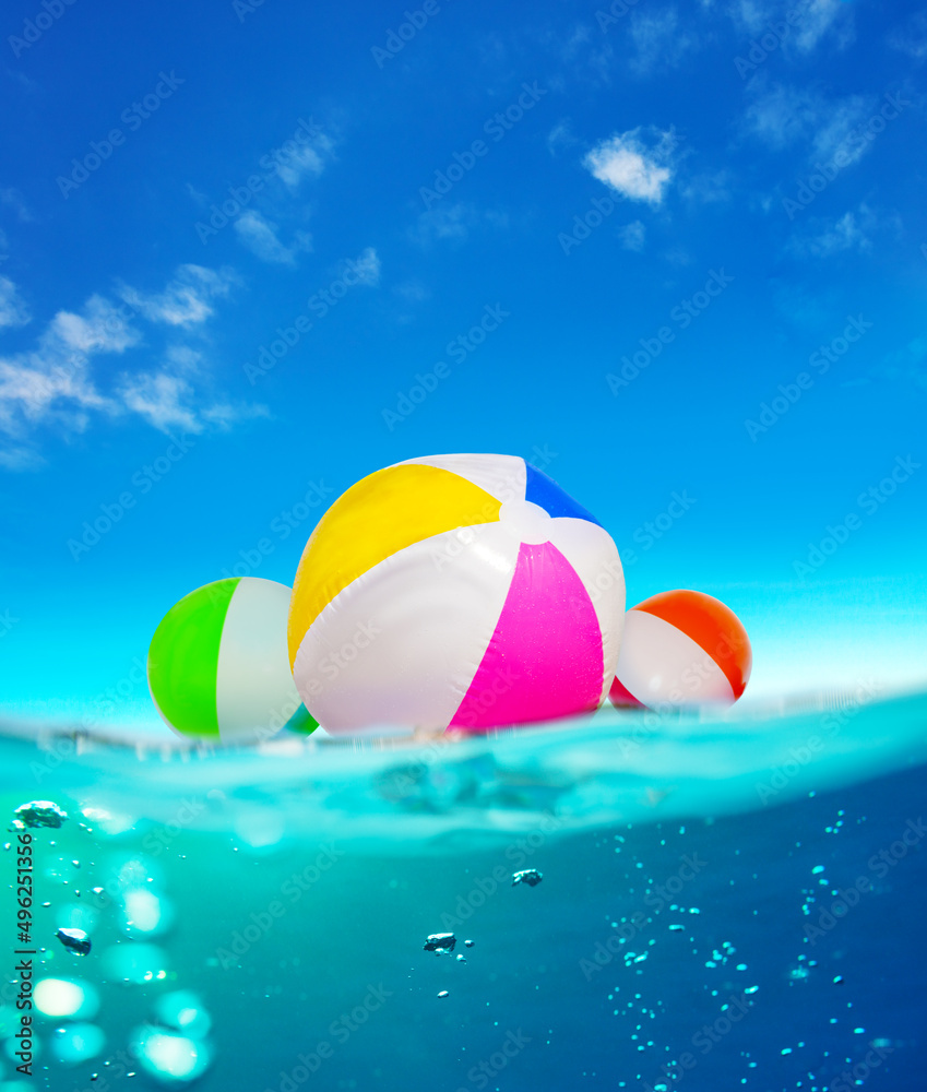 Inflatable balls float in water, split underwater sea image