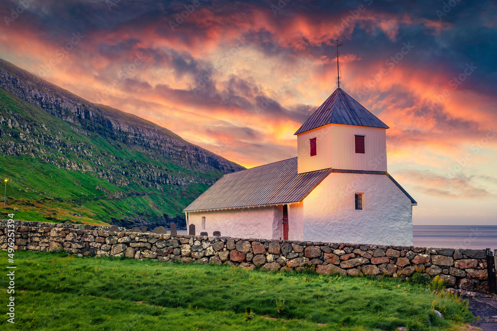 Fototapeta premium Stunning summer view of medieval Olaf's Church in Kirkjubour village. Great sunrise in Faroe Islands, Denmark, Europe. Calm morning scene of Hestur Island. Traveling concept background.