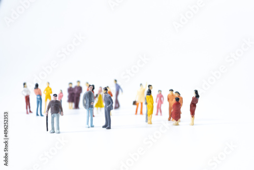 Group of miniature people meeting on white background.