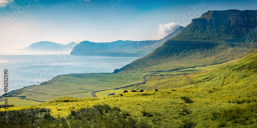 Misty summer view of Faroe Islands with winding country road. Splendid morning scene of outskirts of Sydradalur village, Streymoy island, Denmark, Europe. Traveling concept background..