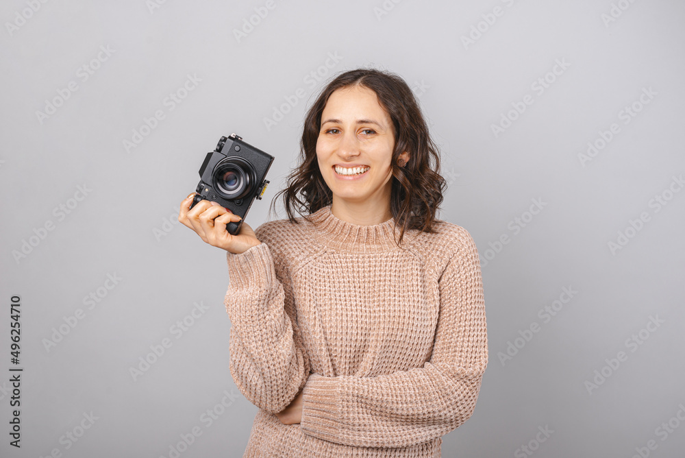 Woman photographer is holding camera in one hand while smiles at the camera. Woman photographer is holding camera in one hand while smiles at the camera.