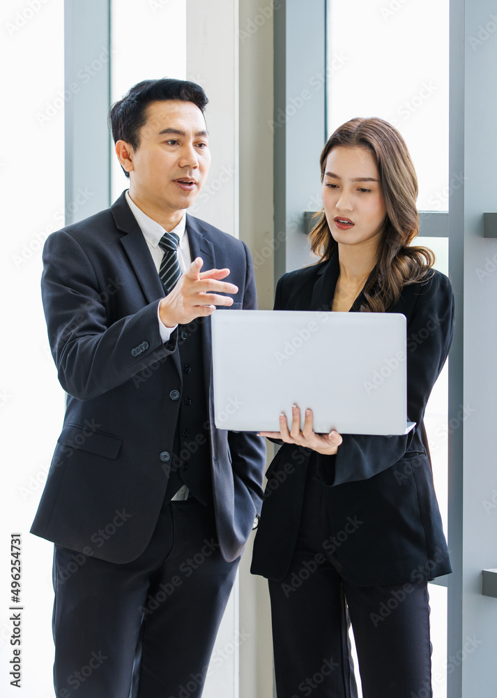 Asian young happy professional successful businessman businesswoman employee partnership in formal business suit standing at working in company meeting room smiling discussing talking together Asian young happy professional successful businessman businesswoman employee partnership in formal business suit standing at working in company meeting room smiling discussing talking together