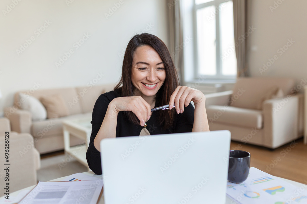 Asian woman working on laptop computer, smiling. Woman Working From Home On Laptop In Modern Apartment. Trendy woman working on laptop from home Asian woman working on laptop computer, smiling. Woman Working From Home On Laptop In Modern Apartment. Trendy woman working on laptop from home