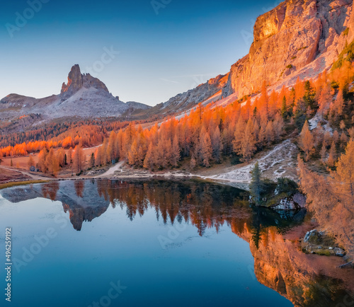 Attractive autumn view of popular tourist destination - Federa lake among red larch trees. Extraordinary sunrise in Dolomite Alps. Gorgeous morning scene of Italy. Beauty of nature concept background.