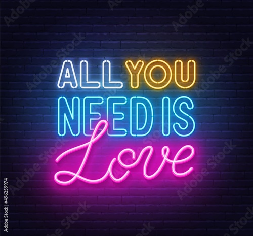 All you need is love neon lettering on brick wall background.