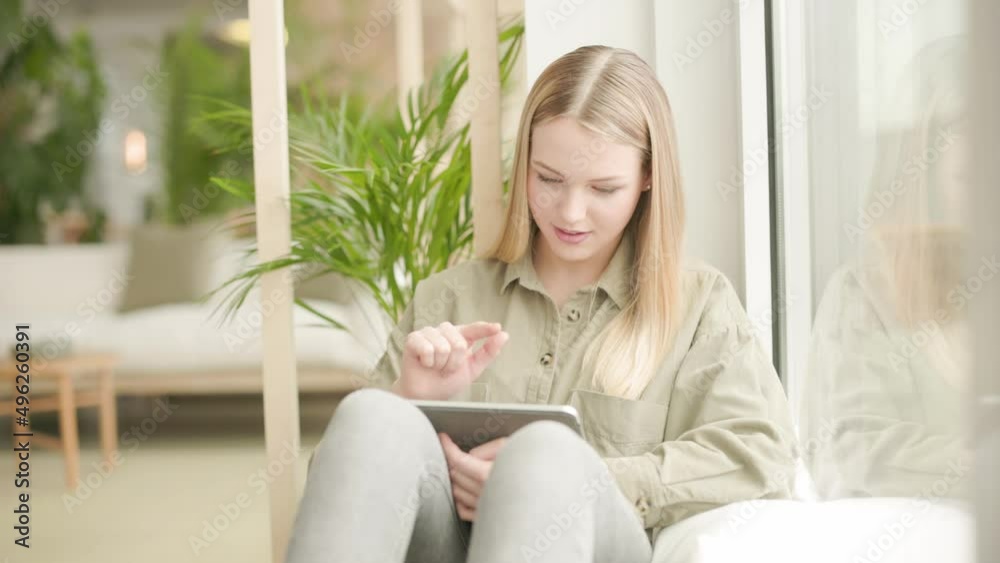 Young woman using digital tablet looking out of window Young woman using digital tablet looking out of window