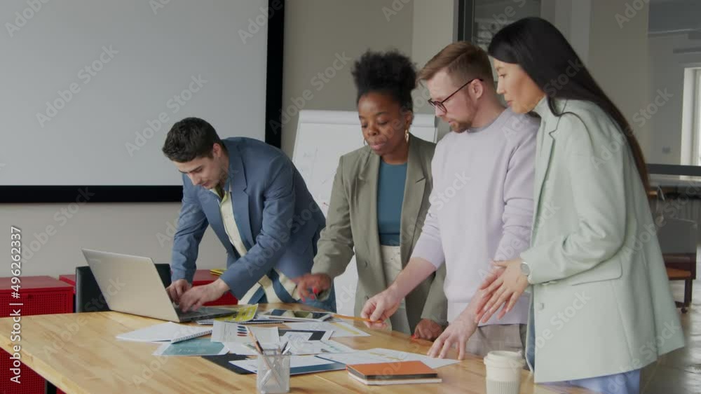Multi ethnic business people analyzing charts in office Multi ethnic business people analyzing charts in office