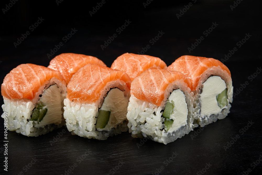 Philadelphia roll sushi with salmon, cucumber and cream cheese on black background for menu. Japanese food Philadelphia roll sushi with salmon, cucumber and cream cheese on black background for menu. Japanese food