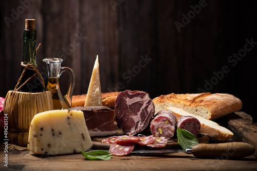 Cutting board with ham, salami, cheese, bread on a rustic wooden board