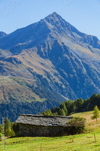 A small and characteristic alpine pasture with typical houses, during a late summer day, near the town of Madesimo, Italy - September 2021.