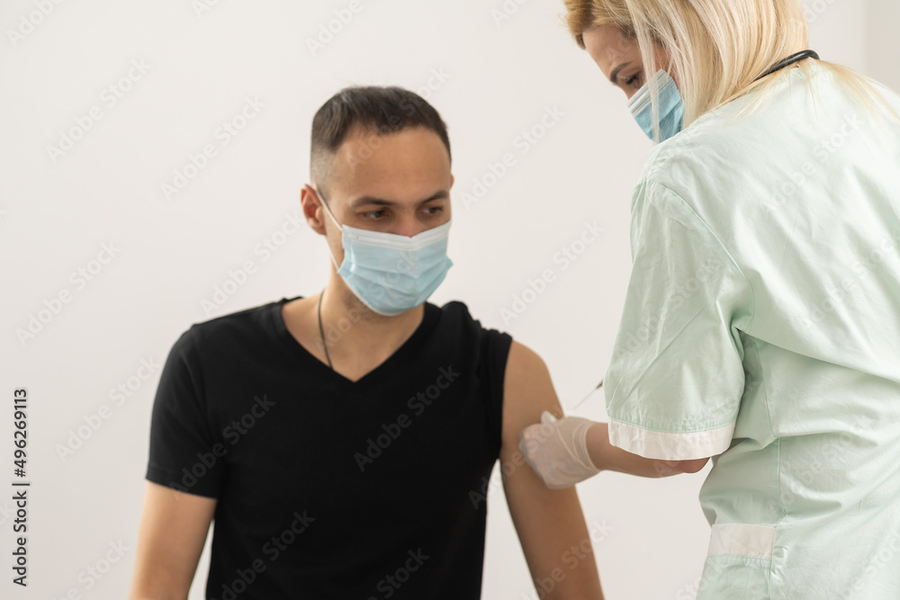 female doctor in gloves holds syringe with vaccine medicine getting ready make vaccination injection from covid-19 coronavirus to sick arab hispanic man patient in medical mask close up