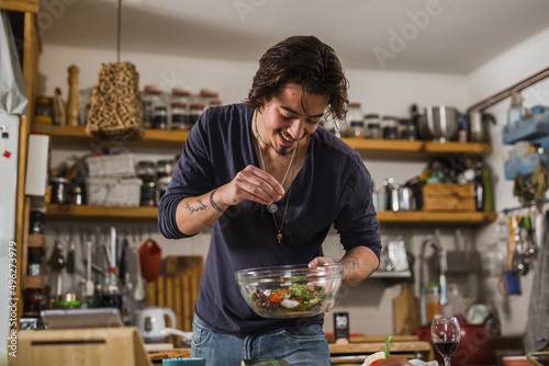 Fotografie man seasoning salad in his kitchen