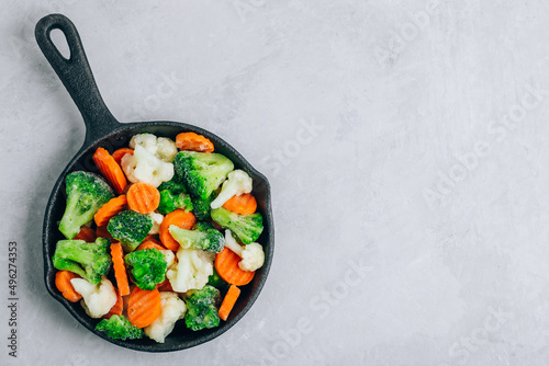 Frozen vegetables. Frozen carrots, broccoli and cauliflower in cast iron pan ready to cook