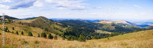 Beautiful nature panoramic view of mountain range. Peaceful landscape. Green hills and fields on summer day. Blue sky with clouds. Panorama of Kopaonik mountain. Serbia. Europe.