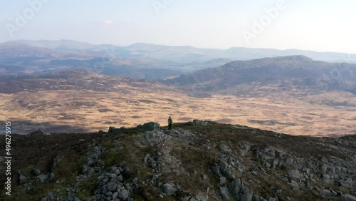 Aerial view of a backpacker standing on top of Rhinog Fach mountain summit in North Wales UK photo