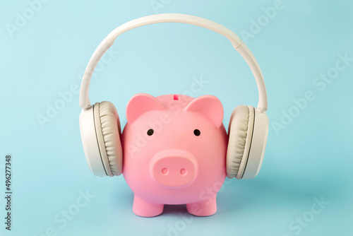 Pink piggy money bank with white wireless headphones photo