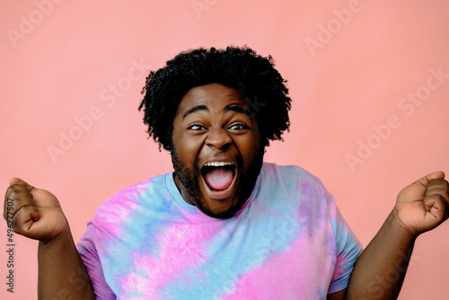 young happy african american man posing in the studio over pink background