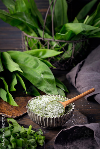 Homemade wild garlic salt and fresh green leaves photo