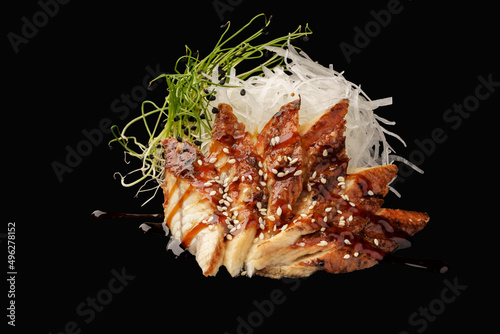 Smoked eel sashimi, daikon, microgreen, unagi sauce, sesame. japanese food on isolated black background, japanese menu.