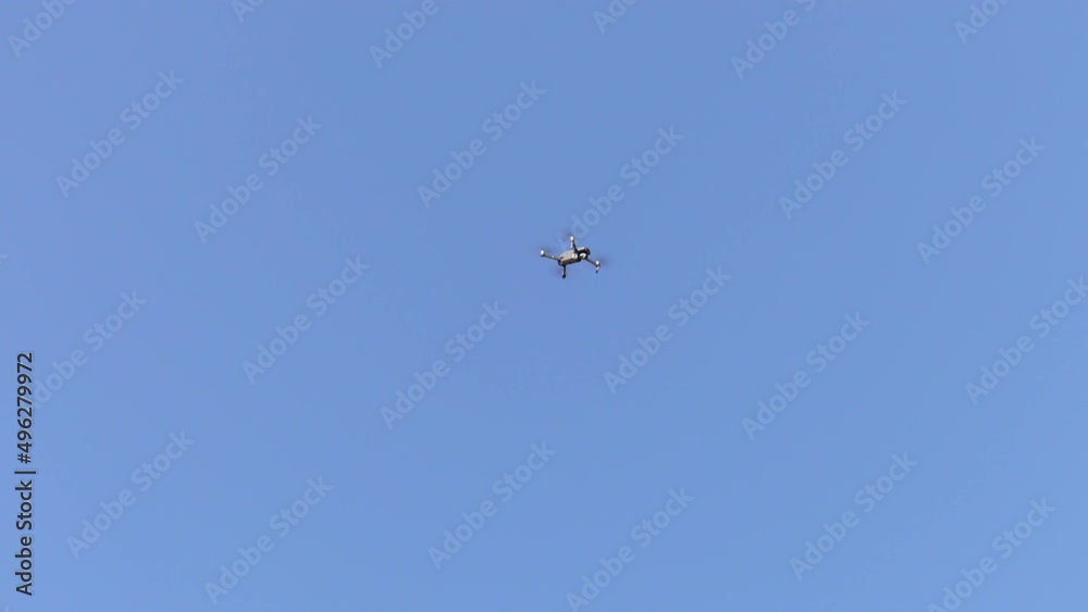 A drone hovering in the air in a blue sky with no clouds A drone hovering in the air in a blue sky with no clouds