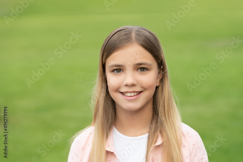 Portrait of happy girl child smiling on green grass background outdoors