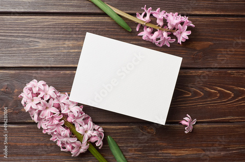 Greeting or invitation card mockup with pink hyacinth flowers on dark wooden background