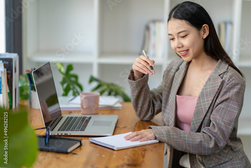 Young adult Asian women work at home or modern office  using a notebook laptop computer. Work from home life  information technology  domestic lifestyle  or self-isolation working concept