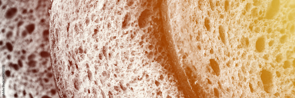 texture of slices white bread as close up background. gray backdrop of rough textured surface chopped pieces loaf of natural organic food with holes. top view. toned black white color. banner. flare texture of slices white bread as close up background. gray backdrop of rough textured surface chopped pieces loaf of natural organic food with holes. top view. toned black white color. banner. flare