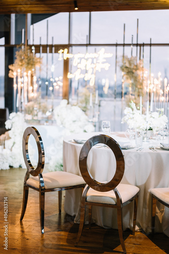 Stylish decoration of a wedding dinner in a classic bohemian style with white tablecloths and vases with white flowers photo