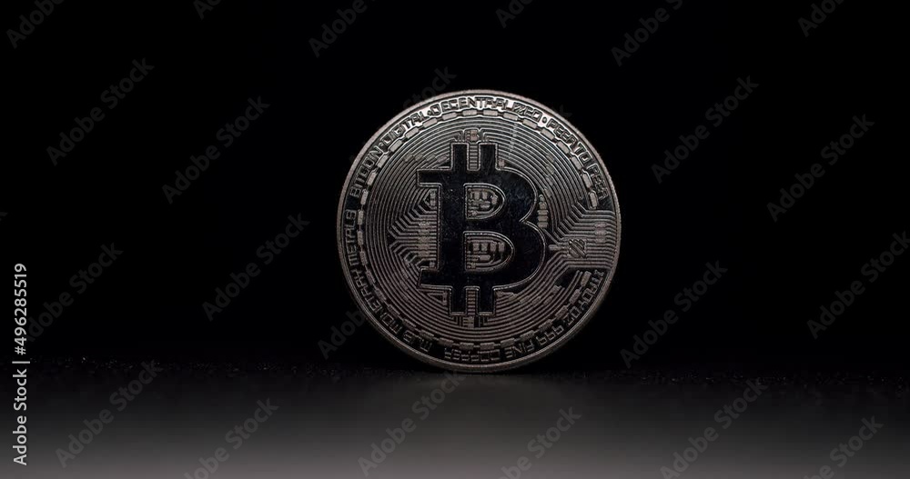 One Bitcoin Close Up. BTC coin. New virtual currency. . Bitcoin cryptocurrency motion shot. Digital coin cyberspace and cryptocurrency. silver BTC coin on black background with lights on coin.
