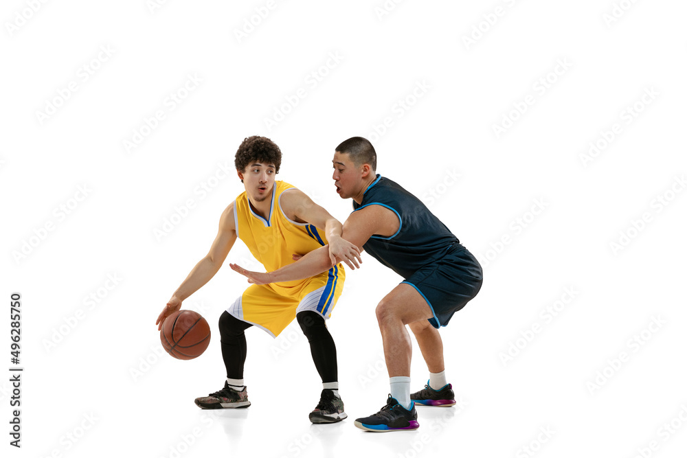 Dynamic portrait of two young basketball players playing basketball isolated on white studio background. Motion, activity, sport concepts.