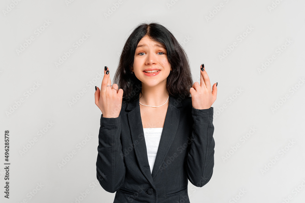 Teen girl cross fingers good luck praying intense, seriously, dreaming achieve goal, waiting important results, making wish, standing grey background anticipating Teen girl cross fingers good luck praying intense, seriously, dreaming achieve goal, waiting important results, making wish, standing grey background anticipating