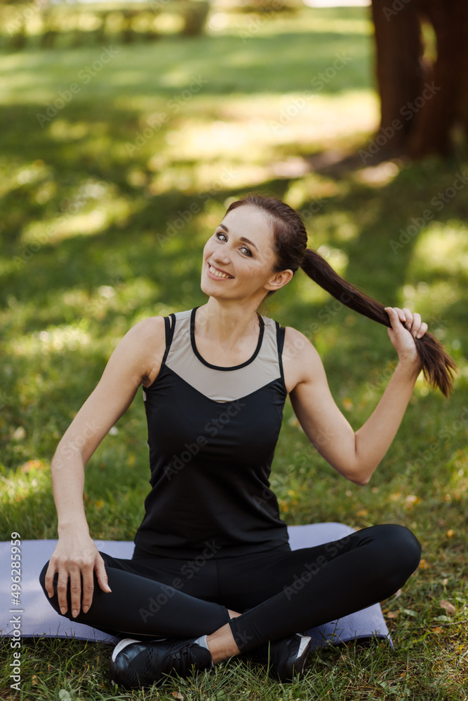 Young woman in sports uniform relaxes and meditates in the city park. Young woman in sports uniform relaxes and meditates in the city park.