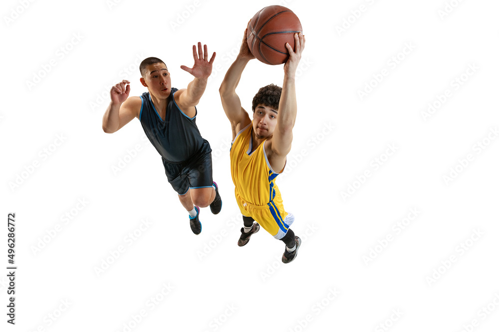 Dynamic portrait of two young basketball players jumping with ball isolated on white studio background. Motion, activity, sport concepts.
