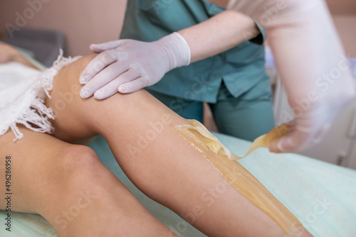 the process of shugaring legs in a beauty salon. The concept of grooming the case photo