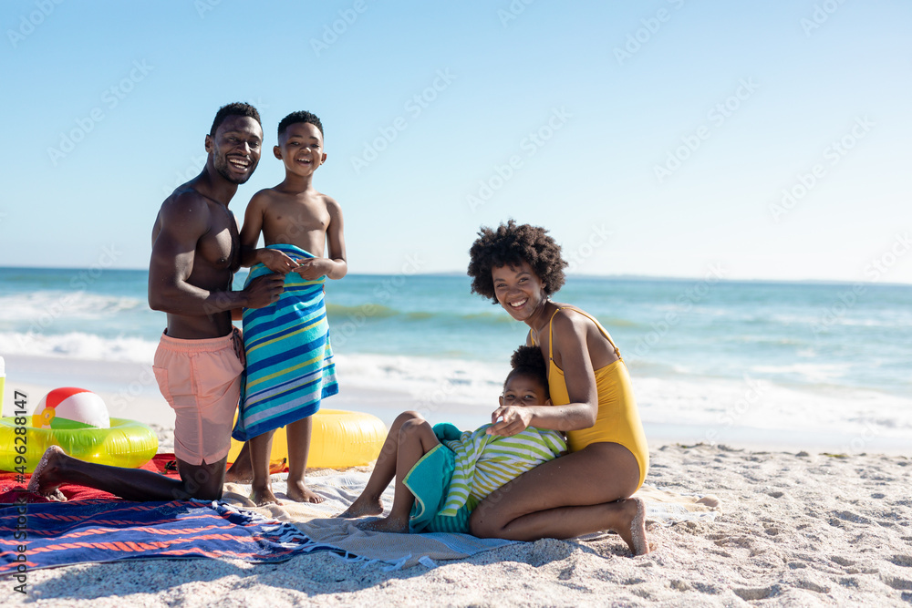 Obraz premium Portrait of smiling african american parents and children enjoying summer holiday at beach