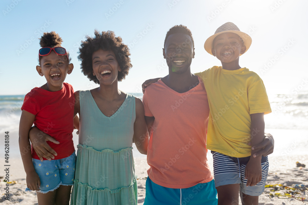 Portrait of smiling african american family with arms around enjoying summer holiday at beach Portrait of smiling african american family with arms around enjoying summer holiday at beach