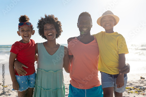 Portrait of smiling african american family with arms around enjoying summer holiday at beach