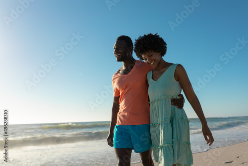 Happy african american couple walking against clear blue sky on sunny day