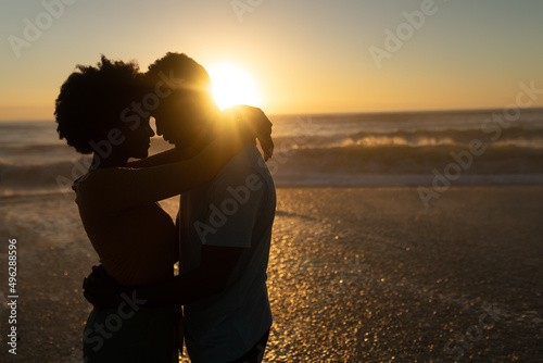 Romantic african american couple spending leisure time together at beach during sunset
