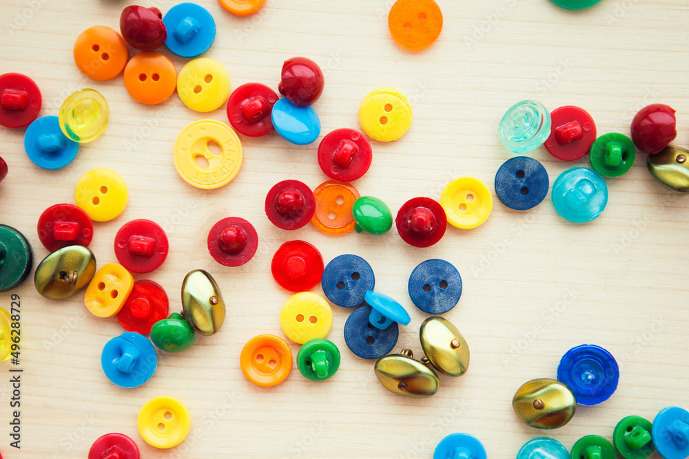 Multicolored buttons on wooden background, flat lay Multicolored buttons on wooden background, flat lay