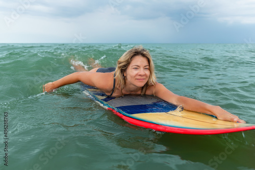 Close-up portrait young adult slim sporty female surfer girl enjoy swimming with surfboard ocean coast wave clear water on sunny day . Sport healthy carefree freedom lifestyle vacation concept © Kirill Gorlov