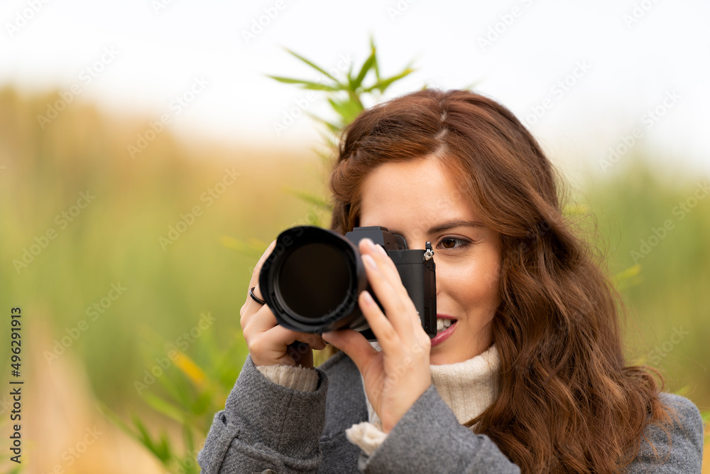 Young woman taking a picture with her photo camera outside
