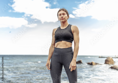 Portrait of a strong athletic woman in sportswear on a wild beach