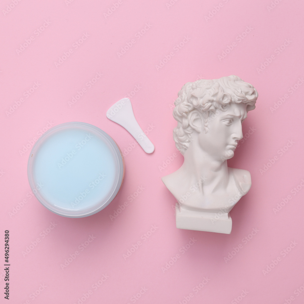 David bust with a jar of cream on a pink background. Skin care concept